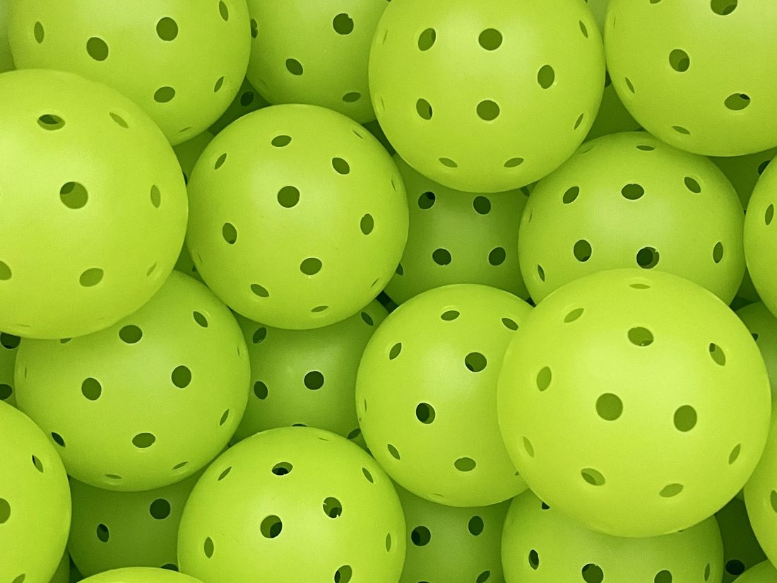 Bin of lime green pickleballs fresh out of rotational molding